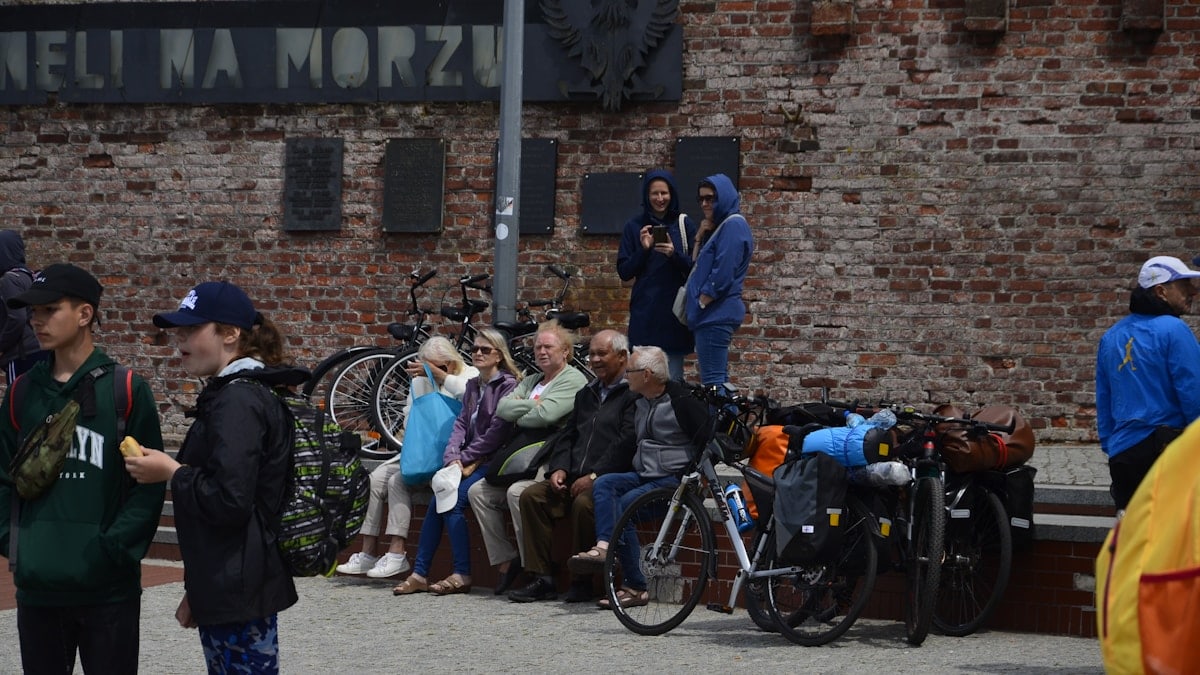 a group of people sitting on a bench next to a brick building